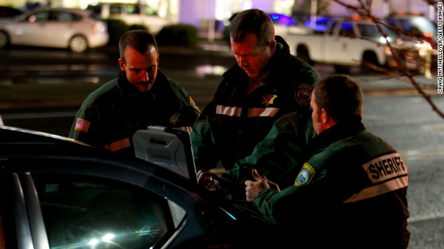 Lt. James Rhodes of the Clackamas County Sheriff's Office works with other responders in the parking lot of the mall.