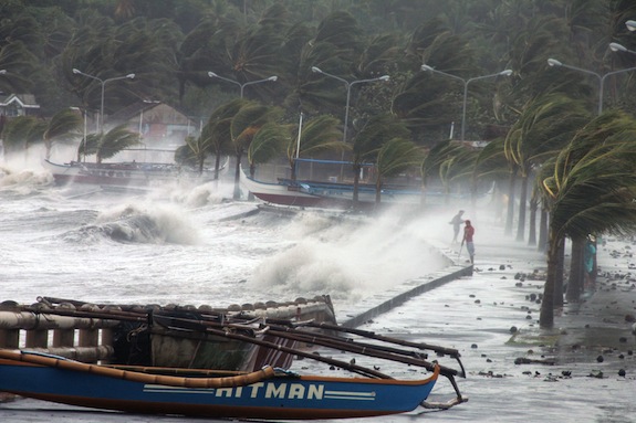 Residents (R) stand along a sea wall as high waves pounded them amidst strong winds as Typhoon Haiyan hit the city of Legaspi, Albay province, south of Manila on November 8, 2013.  One of the most intense typhoons on record whipped the Philippines on November 8, killing three people and terrifying millions as monster winds tore roofs off buildings and giant waves washed away flimsy homes.AFP PHOTO/CHARISM SAYAT        (Photo credit should read Charism SAYAT/AFP/Getty Images)