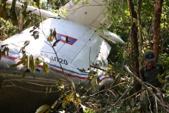 Rescue worker makes his way past the wreckage of an air force plane crash in Laos