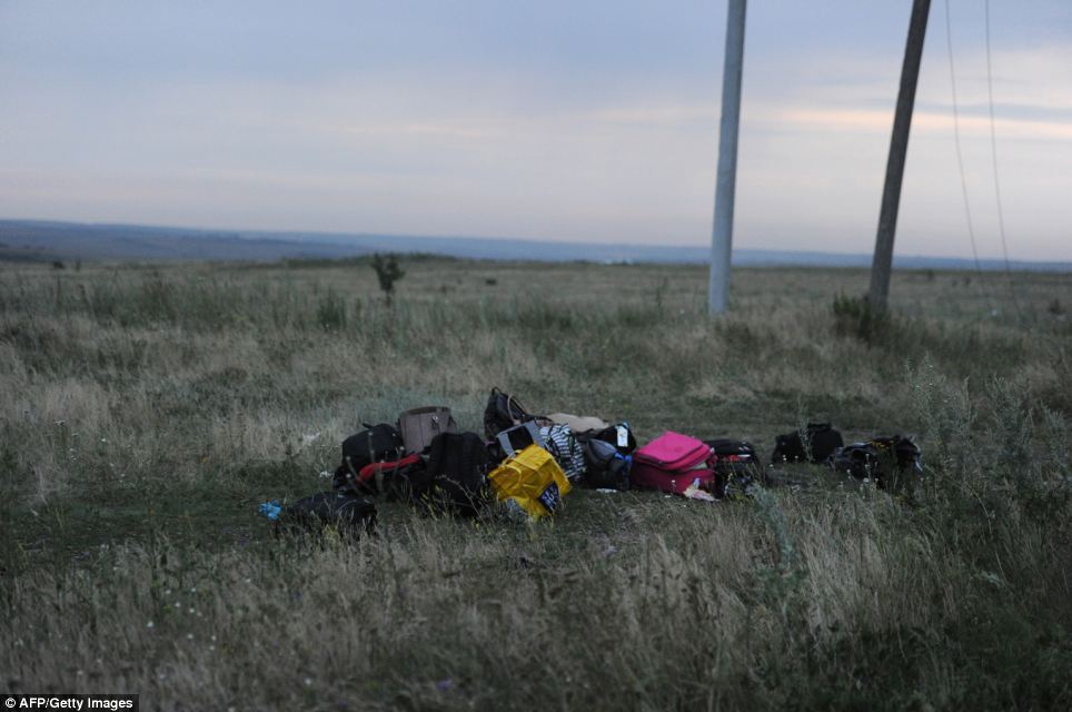 Discarded: Luggage from the plane is piled up at the crash site by rescue workers performing recovery work in east Ukraine