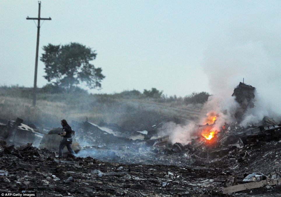 Burning: Rescue workers walk through the burning wreckage of the plane after it crashed near the town of Shaktarsk in rebel-held east Ukraine