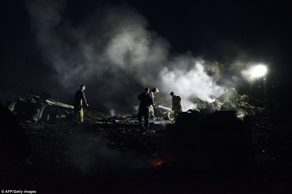 Picking up the pieces: Work at the crash site continued into the night, as world leaders called for a full investigation into the tragedy