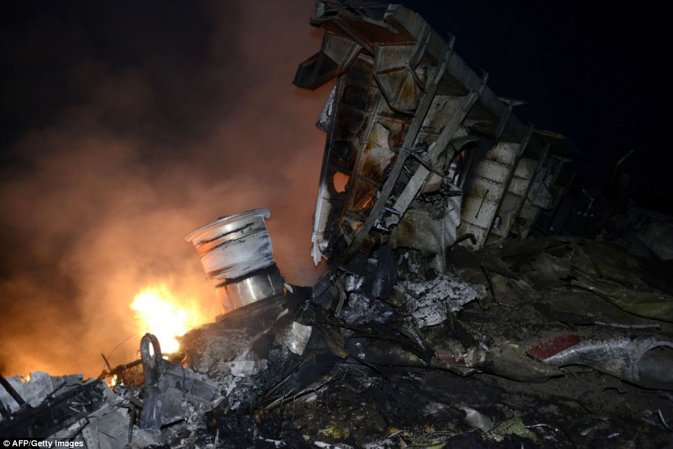 Fighting the fire: Airline fuel continues to burn amongst the wreckage as night falls over the crash site