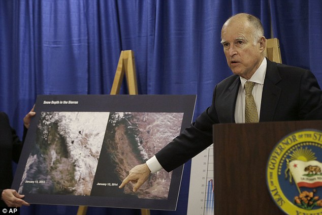 Low and dropping: Governor Jerry Brown points to images showing the snow depth in the Sierra mountains on January 13, 2013 (left) and January 13, 2014 (center) while declaring a drought state of emergency in San Francisco