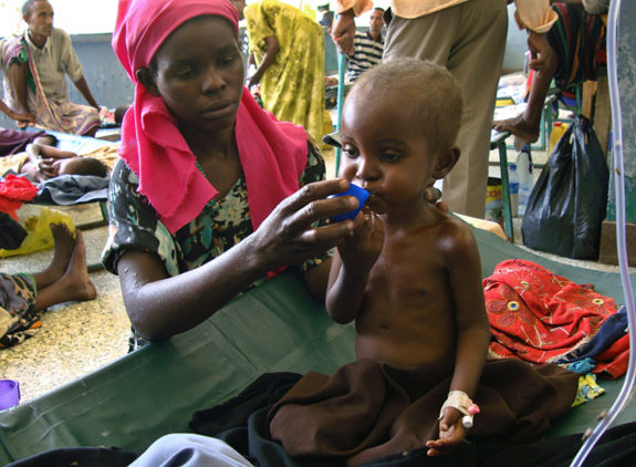 Nearly four million Somalians are at risk of starvation. The United Nations has <a href="http://articles.nydailynews.com/2011-07-21/news/29818545_1_somalia-somali-refugees-rashid-abdi" target="_blank">declared a famine</a> in two regions of Southern Somalia, with nearly half the African nation's population in need of humanitarian aid. Somalia and other East African nations are enduring the worst drought conditions in 60 years, leading to massive crop failures. Somalians now fight for their survival.
<br><br>
Above, a severely malnourished Somali child receives Oral Rehydration Salts.