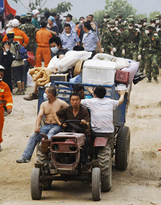 People carry their belongings on a tractor as they evacuate Mianyang, one of the cities hit hard by the earthquake.