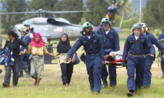 Tsunami victims are led from helicopter to medical facilities at Banda Aceh airport Saturday. (AP/Andy Eames)